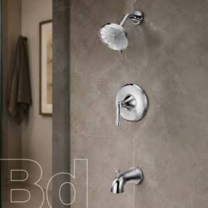 Chrome showerhead, tub spout, and single-handle valve mounted on a gray tiled shower wall.