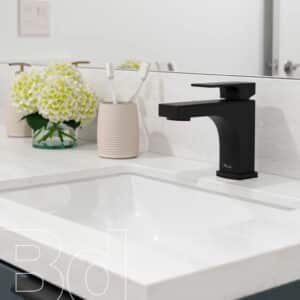 Modern matte-black bathroom faucet on a white countertop beside a vase of white flowers and a toothbrush holder; 'B30' watermark visible in the lower left.