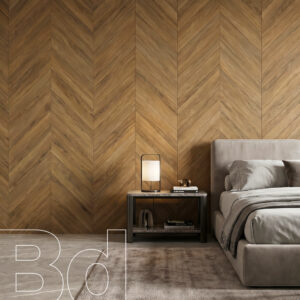 Modern bedroom scene with a herringbone wood wall, a gray upholstered bed, and a nightstand with a lamp and stacked books.