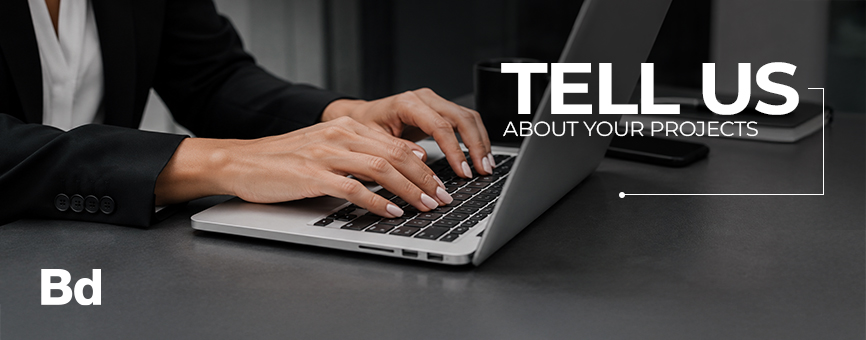 Person typing on a laptop at a dark desk with a 'Tell Us About Your Projects' banner overlay